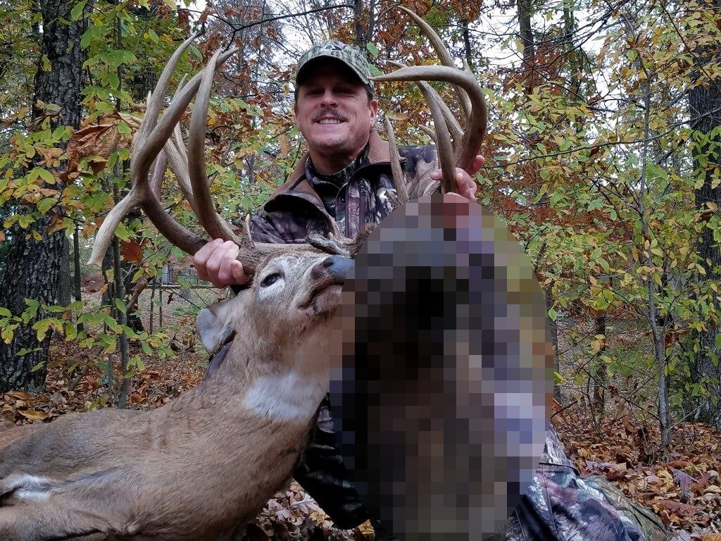A hunter with a deer and a section next to its head that is blurred out