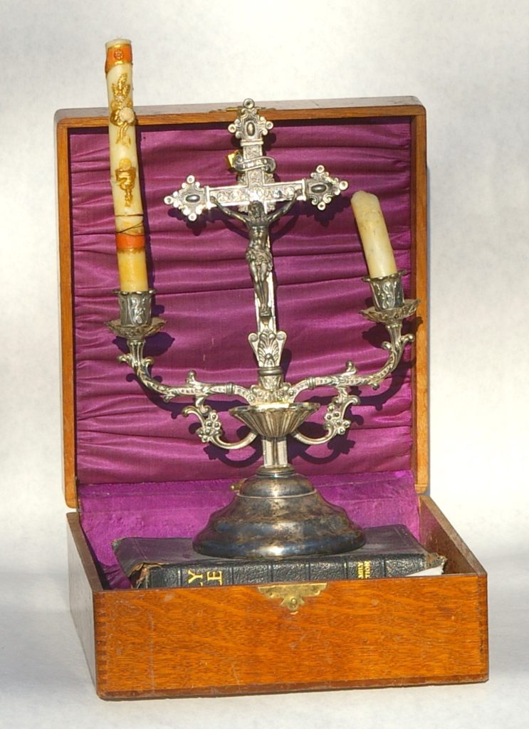 An old wooden box with a bible, crucifix and candles